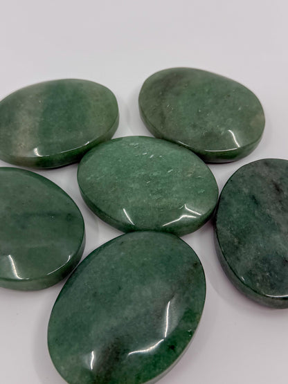 Five polished green aventurine oval palm stones arranged on a plain white background.